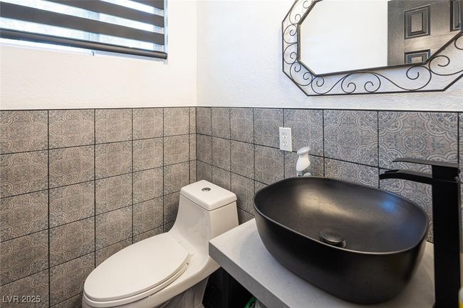 Bathroom with a wainscoted wall, toilet, tile walls, and a sink | Image 31