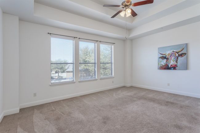Carpeted spare room featuring a tray ceiling, a ceiling fan, and baseboards | Image 22