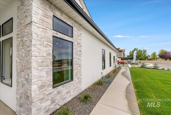 View of side of property featuring stucco siding, stone siding, and a lawn | Image 39