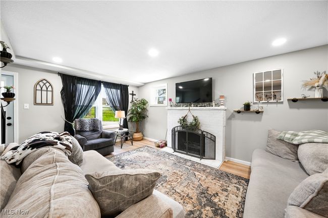 Living area with a fireplace, wood finished floors, recessed lighting, and baseboards | Image 7