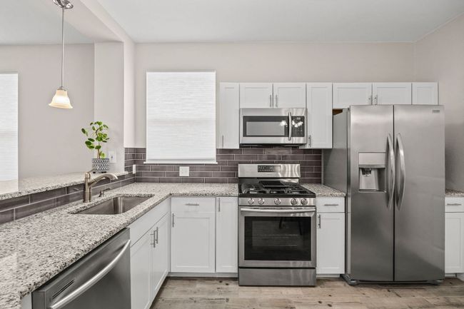 Kitchen with a sink, white cabinets, stainless steel appliances, and tasteful backsplash | Image 16