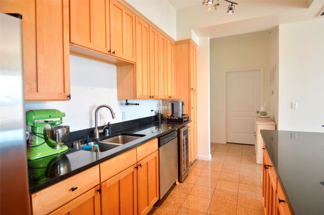 Kitchen featuring stainless steel appliances, dark stone counters, light brown cabinets, and wine cooler | Image 30