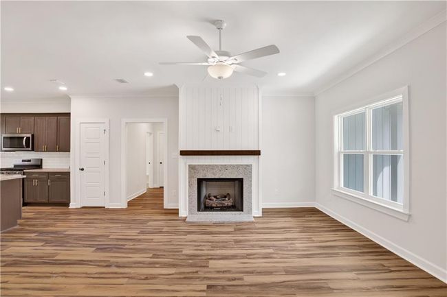 Unfurnished living room with ornamental molding, baseboards, light wood-type flooring, recessed lighting, and a ceiling fan | Image 9