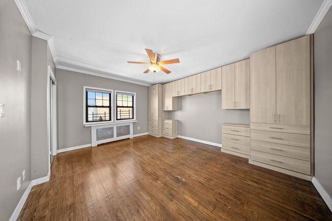 Unfurnished bedroom featuring crown molding, dark wood finished floors, baseboards, and a ceiling fan | Image 22