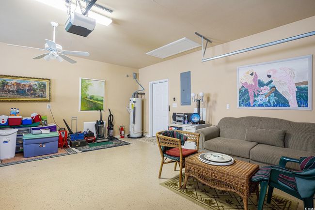Garage featuring water heater, attic access, electric panel, a ceiling fan, and speckled floor | Image 24