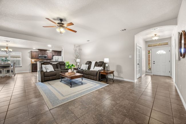 Living area featuring arched walkways, ceiling fan, a chandelier, and a textured ceiling | Image 5