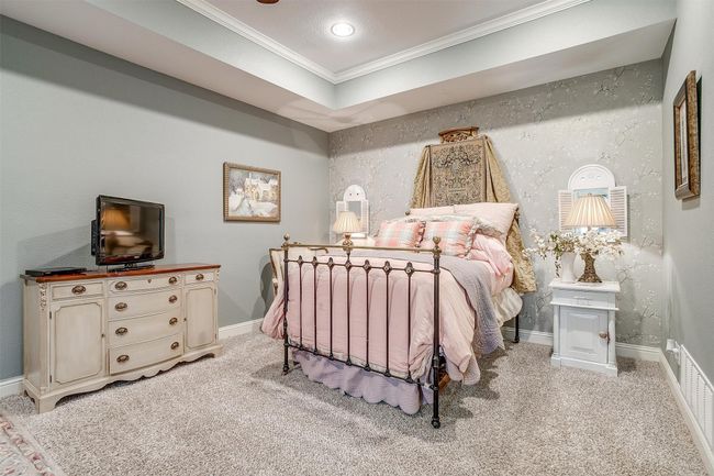 Bedroom featuring baseboards, a raised ceiling, crown molding, and light carpet | Image 5