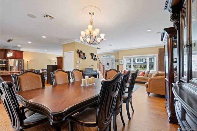 Dining area featuring ornamental molding, stairway, a chandelier, light wood-type flooring, and recessed lighting | Image 5