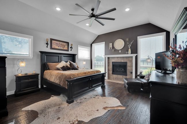 Bedroom with a fireplace, lofted ceiling, dark wood-type flooring, and ceiling fan | Image 14