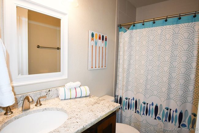 Bathroom with toilet, vanity, and curtained shower | Image 20
