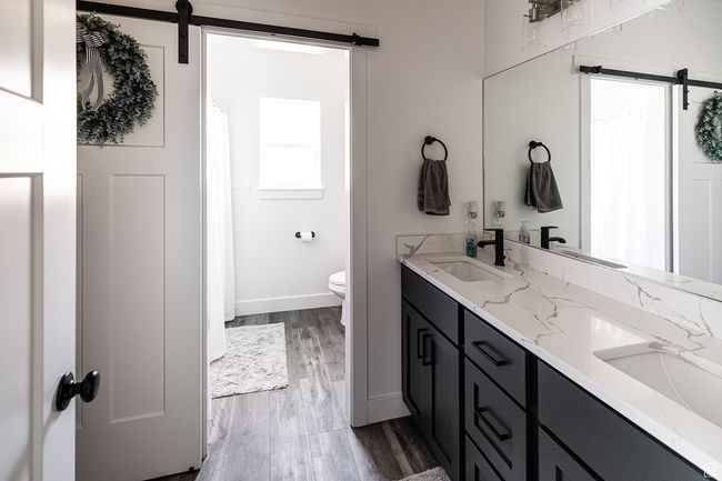 Full bath with a sink, double vanity, baseboards, toilet, and wood finished floors | Image 23
