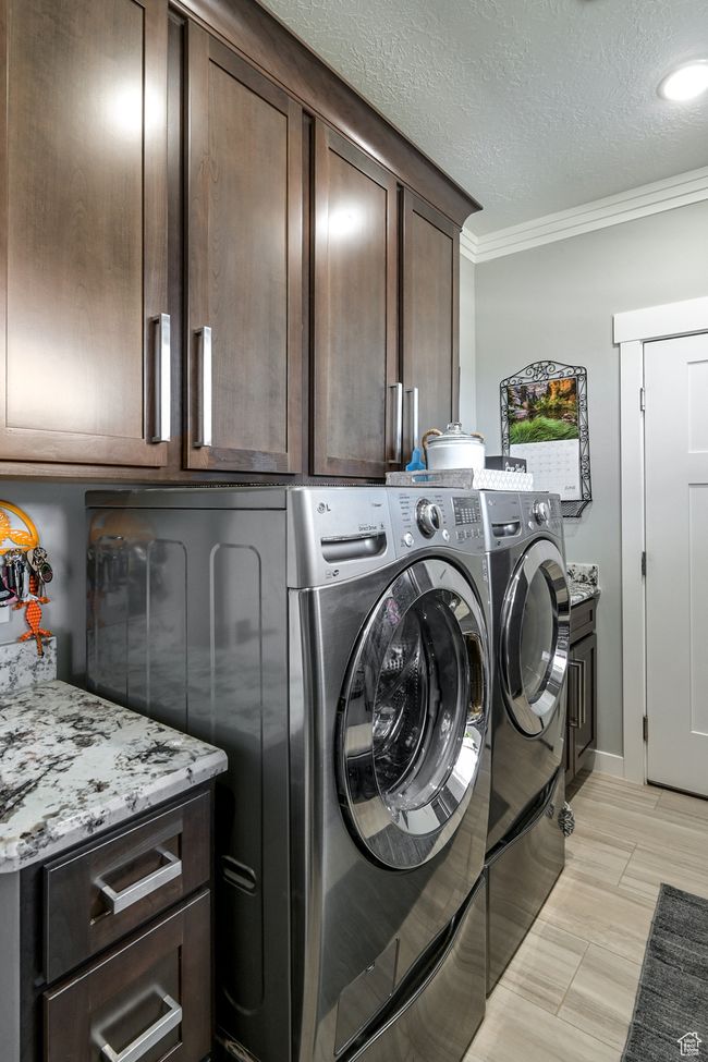 Laundry area with cabinet space, washer and dryer, crown molding, and a textured ceiling | Image 35