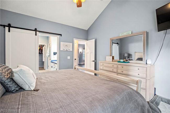 Bedroom with a spacious closet, a barn door, high vaulted ceiling, a closet, and ceiling fan | Image 20