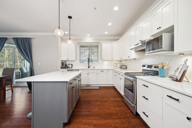 Kitchen with ornamental molding, under cabinet range hood, decorative backsplash, stainless steel appliances, and a sink | Image 12