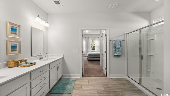 Ensuite bathroom with double vanity, a stall shower, wood tiled floors, and baseboards | Image 21
