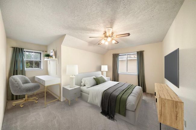 The upstairs bedroom offers a flexible layout with space for both a bed and a dedicated work or study area, featuring neutral carpet and dual windows for natural light. This photo has been virtually staged. | Image 26