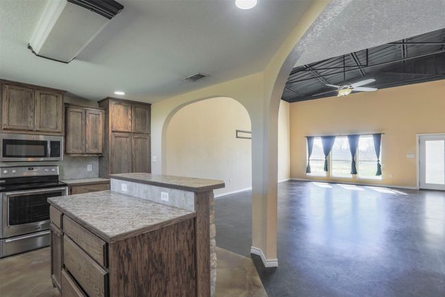 Kitchen with stainless steel appliances, open floor plan, visible vents, and a kitchen island | Image 8