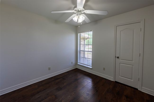 Unfurnished room featuring a ceiling fan, baseboards, and dark wood-style flooring | Image 34
