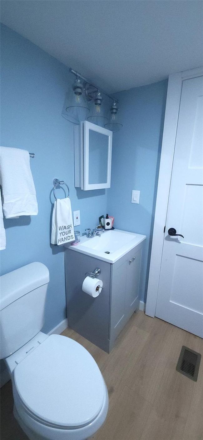 Bathroom with vanity, visible vents, toilet, wood finished floors, and baseboards | Image 15