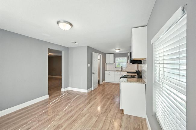 Kitchen with light wood-type flooring, tasteful backsplash, white cabinetry, and electric range | Image 4