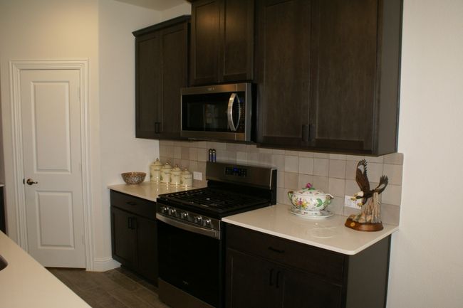 Kitchen featuring light countertops, dark brown cabinetry, appliances with stainless steel finishes, and tile backsplash | Image 13
