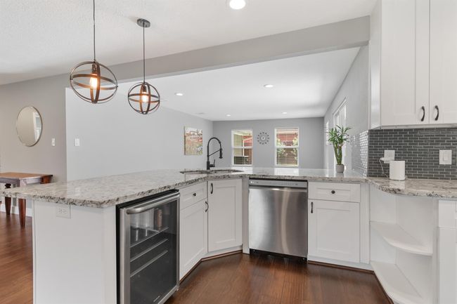 Another view of the kitchen with large breakfast bar with pendant lighting. The kitchen also has built in shelving and views throughout the main living areas. | Image 14