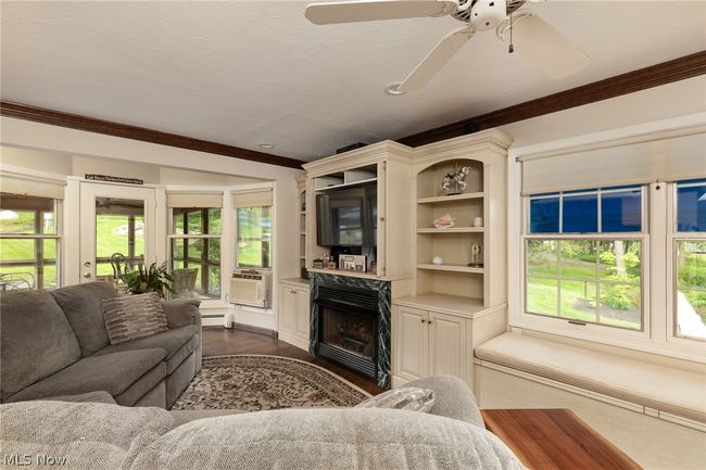 Living room with dark hardwood / wood-style floors, ceiling fan, ornamental molding, baseboard heating, and a high end fireplace | Image 27