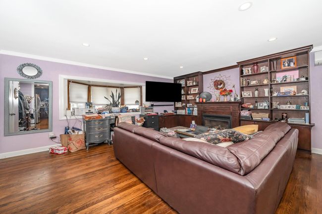 Living room featuring crown molding, wood finished floors, a fireplace, baseboards, and recessed lighting | Image 20