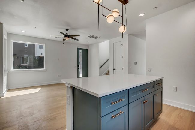 Kitchen with ceiling fan, light wood finished floors, light countertops, hanging light fixtures, and baseboards | Image 9