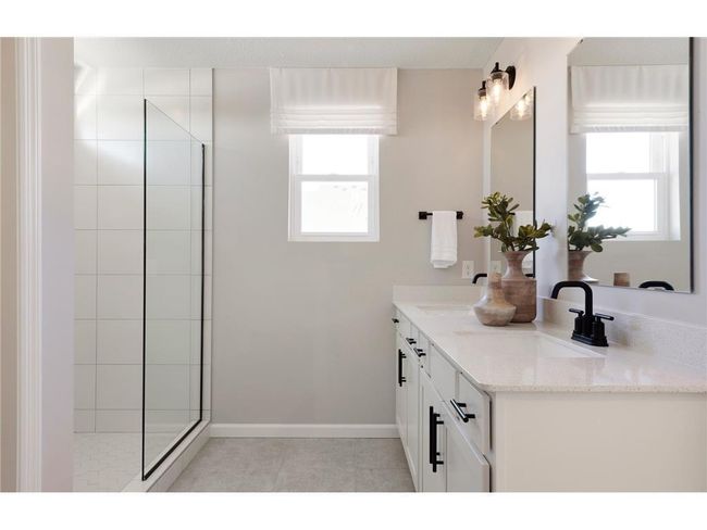 Perfectly located off the bedroom is the Primary Bathroom. This bathroom features modern finishings such as white cabinetry with quartz countertops mixed with the comfort of your double sink vanity and roomy shower! Photo of model home. | Image 33