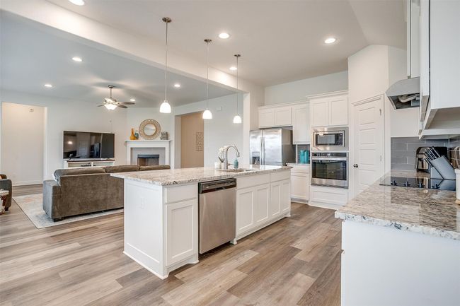 Kitchen with appliances with stainless steel finishes, a sink, a ceiling fan, white cabinets, and recessed lighting | Image 14