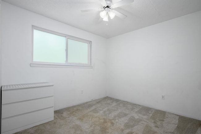 Empty room with light carpet, a ceiling fan, and a textured ceiling | Image 32