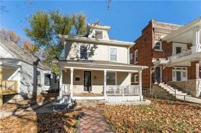 A stunning brick walkway leads to a home with a spacious and inviting front porch. | Image 1