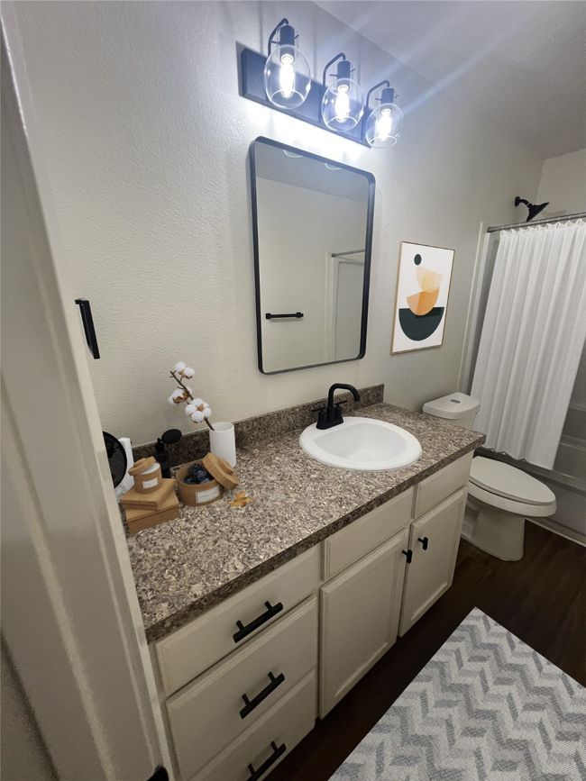 Full bath featuring toilet, wood finished floors, shower / tub combo, and vanity | Image 6