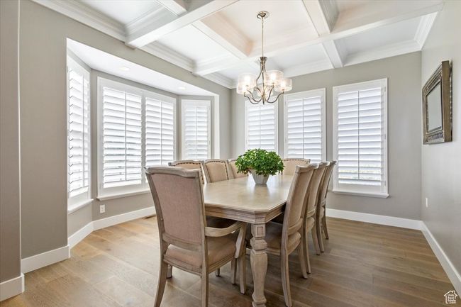 Dining room featuring healthy amount of natural light, coffered ceiling, a chandelier, baseboards, and light wood-style flooring | Image 8