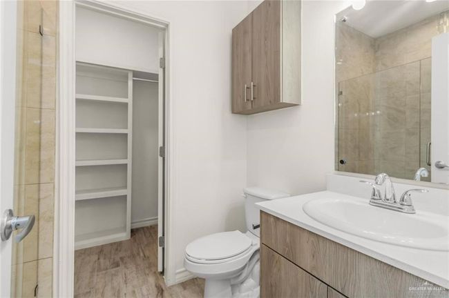 Bathroom featuring a spacious closet, vanity, and wood finished floors | Image 9