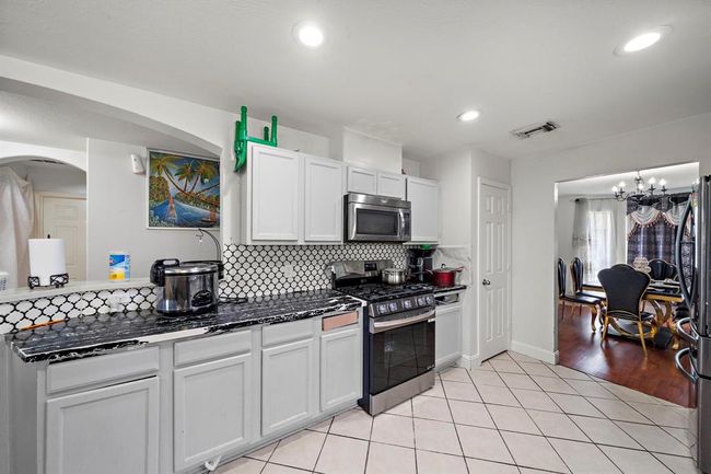 Located at the heart of the home, this spacious kitchen has been tastefully refreshed with bold countertops, painted cabinets, and contemporary tile work. The open layout provides effortless access to the breakfast nook and living room, making it ideal for everything from quiet mornings to weekend entertaining. | Image 11