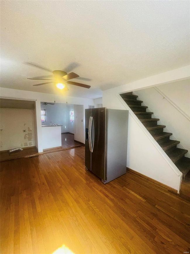Unfurnished living room featuring a textured ceiling, stairway, a ceiling fan, and wood-type flooring | Image 11
