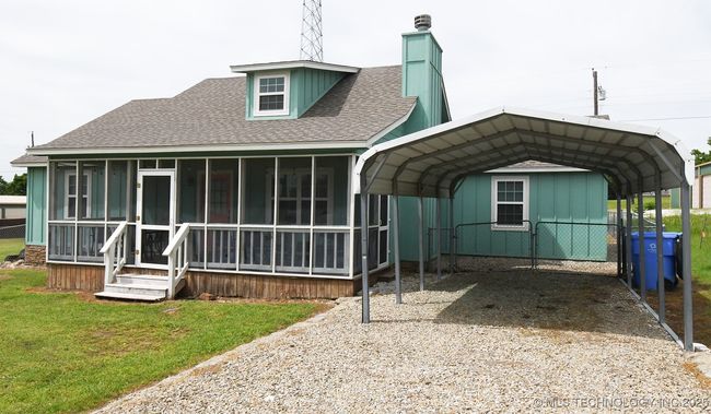 Back of property with a sunroom, roof with shingles, a chimney, a detached carport, and driveway | Image 28