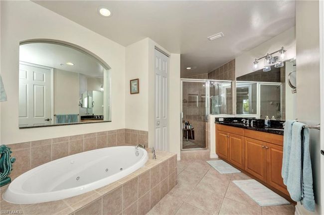 Bathroom with a tub with jets, vanity, a shower stall, tile patterned flooring, and recessed lighting | Image 22