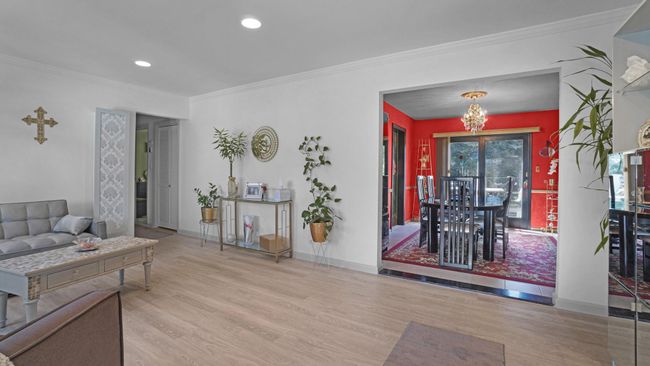Living area with crown molding, baseboards, a chandelier, and wood finished floors | Image 6