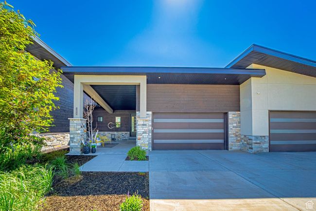 Entrance to property with stone siding, driveway, and an attached garage | Image 23
