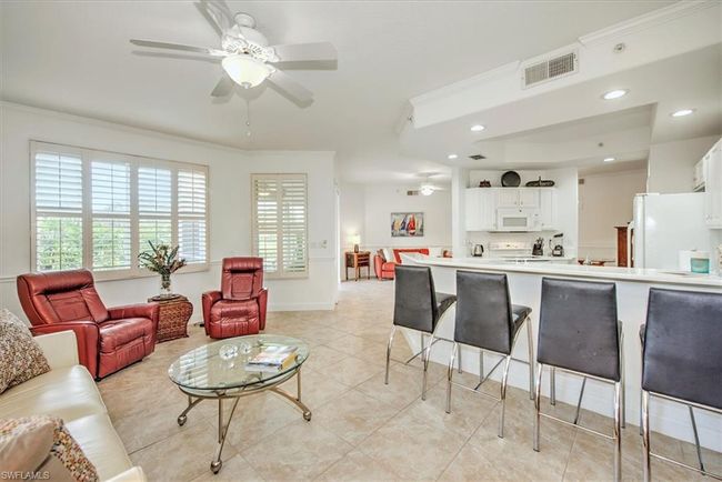 Living room with a wealth of natural light, visible vents, crown molding, and a ceiling fan | Image 8