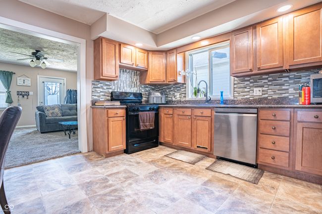 kitchen with dishwasher, decorative backsplash, black gas range, and ceiling fan | Image 7