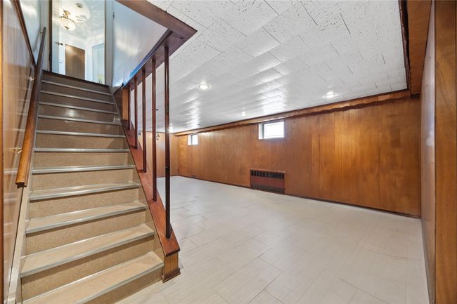 Staircase with tile patterned floors, wood walls, and radiator | Image 14