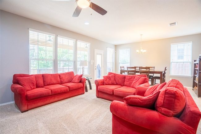 Living area with a ceiling fan, healthy amount of natural light, a chandelier, and light colored carpet | Image 10