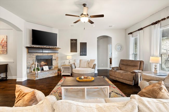 Living area with visible vents, baseboards, dark wood finished floors, arched walkways, and a stone fireplace | Image 13