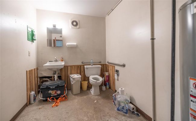 Bathroom with unfinished concrete floors, toilet, and a sink | Image 22