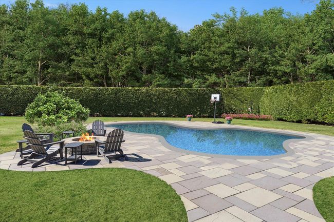 View of pool featuring a lawn, a fire pit, fence, and a patio area | Image 40