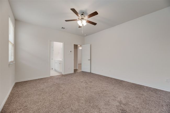 Unfurnished bedroom with light carpet, baseboards, connected bathroom, and a ceiling fan | Image 23
